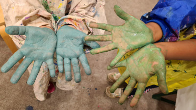 Zwei Paar Kinderhände voller Acrylfarbe